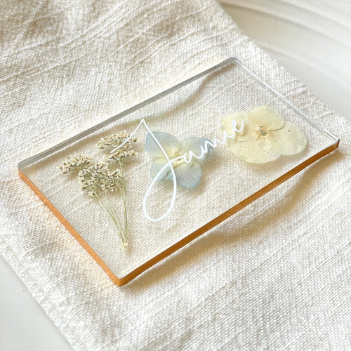 pressed blue flower place cards with gold lining on plate setting
